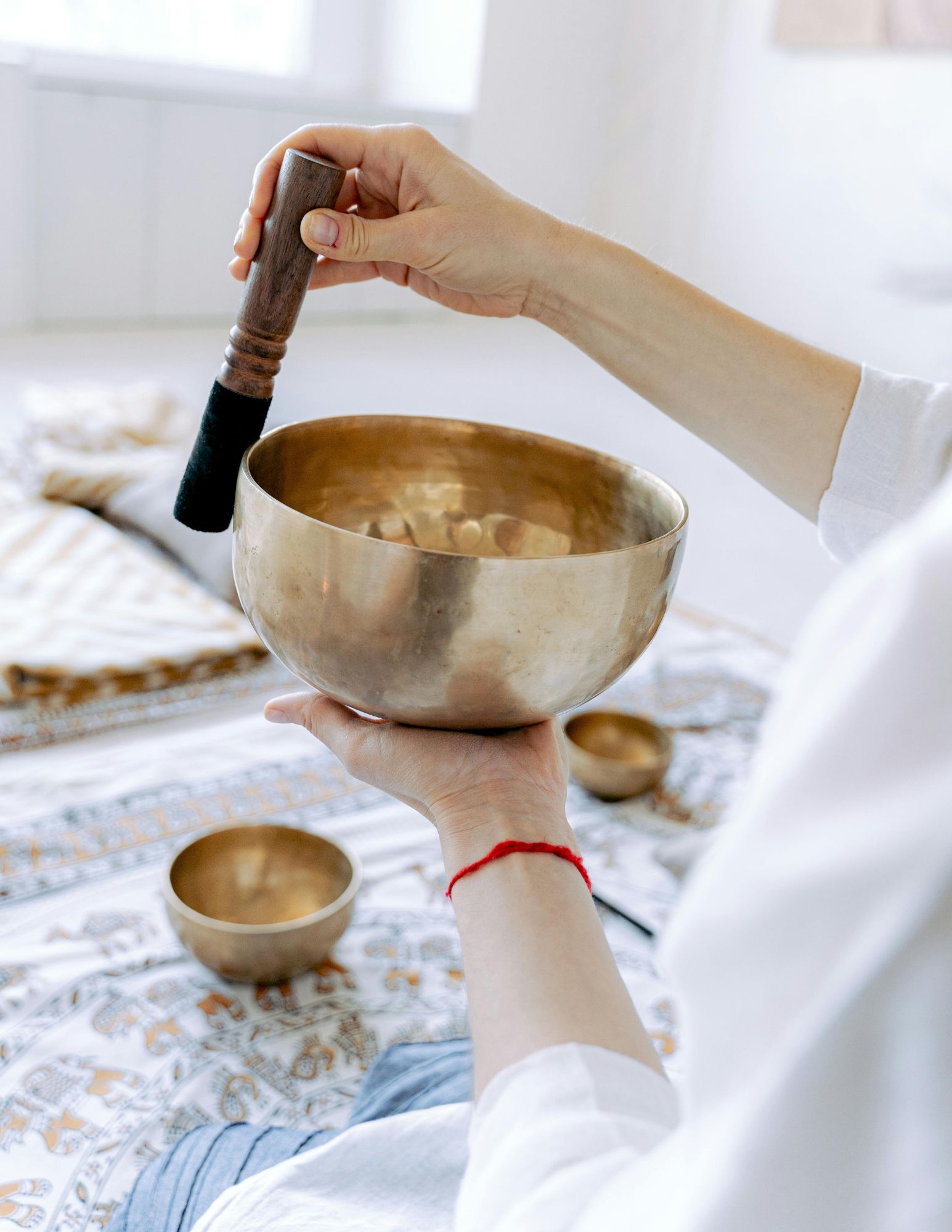 Person playing a Tibetan singing bowl for sound healing therapy at a wellness retreat in Kerala.