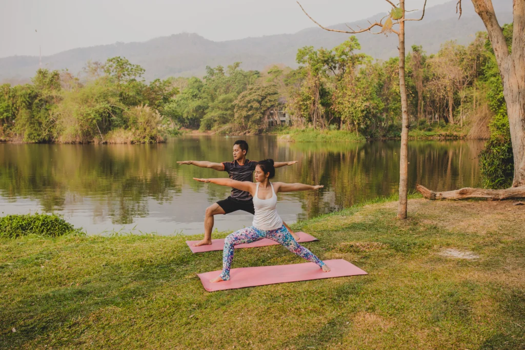 Couple practicing yoga by the riverside at Retreat Inn Kerala, surrounded by lush greenery and serene nature.