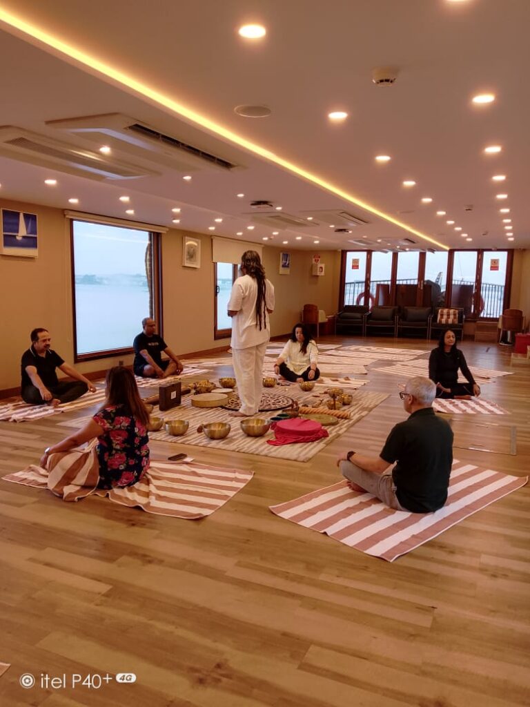 Group sound bath healing session at Retreat Inn Kerala Ayurveda Yoga Resort with crystal singing bowls in a serene wellness studio overlooking nature